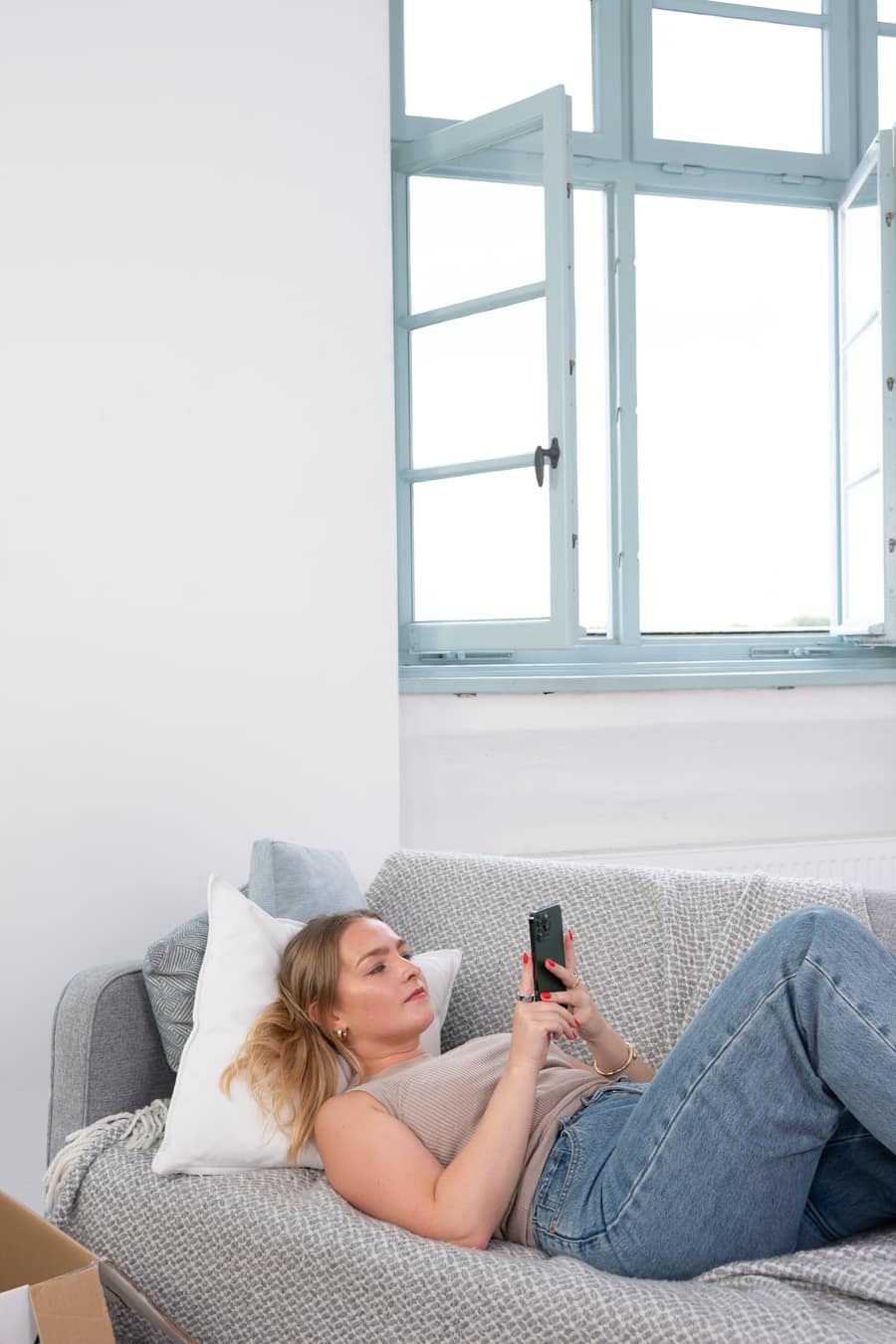 Person nutzt die MUVN App neben einem Umzugskarton